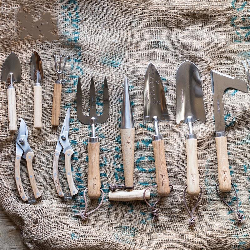 Rustic style pruning shears and gardening tools with wooden handles and stainless steel blades, arranged on a wooden surface.