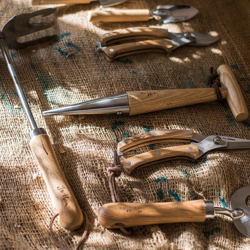 Rustic style pruning shears and gardening tools with wooden handles and stainless steel blades, arranged on a wooden surface.