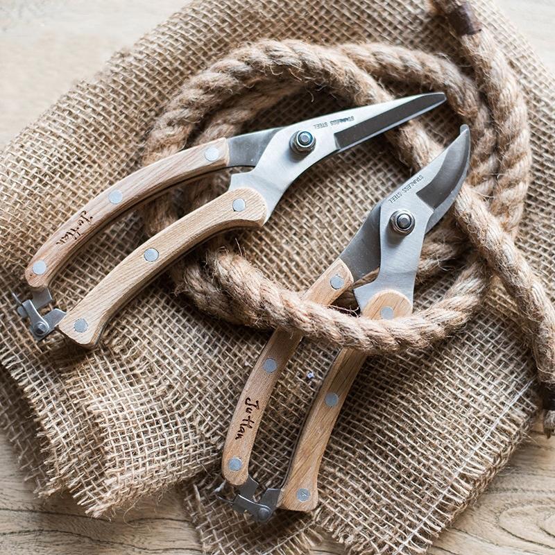 Rustic style pruning shears and gardening tools with wooden handles and stainless steel blades, arranged on a wooden surface.