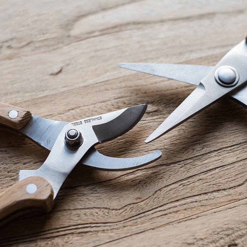 Rustic style pruning shears and gardening tools with wooden handles and stainless steel blades, arranged on a wooden surface.