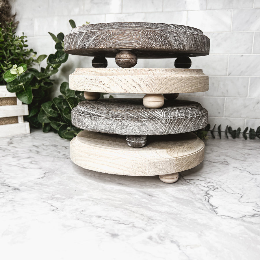 A rustic wooden stand with three legs, showcasing a distressed white finish, perfect for home decor.