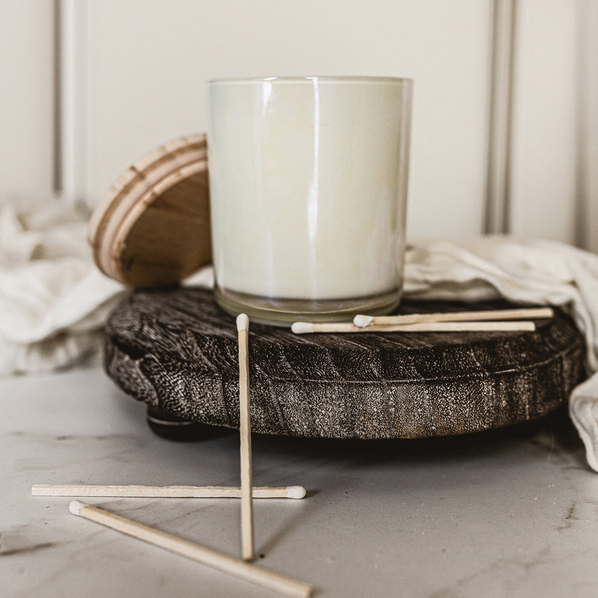 A rustic wooden stand with three legs, showcasing a distressed white finish, perfect for home decor.