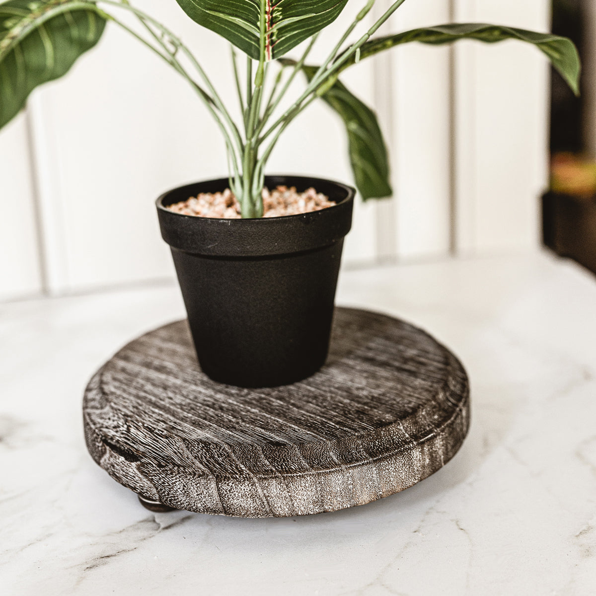 A rustic wooden stand with three legs, showcasing a distressed white finish, perfect for home decor.