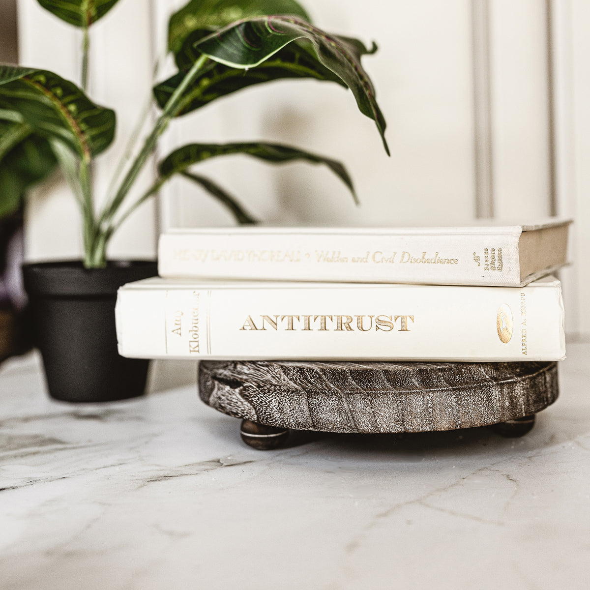 A rustic wooden stand with three legs, showcasing a distressed white finish, perfect for home decor.