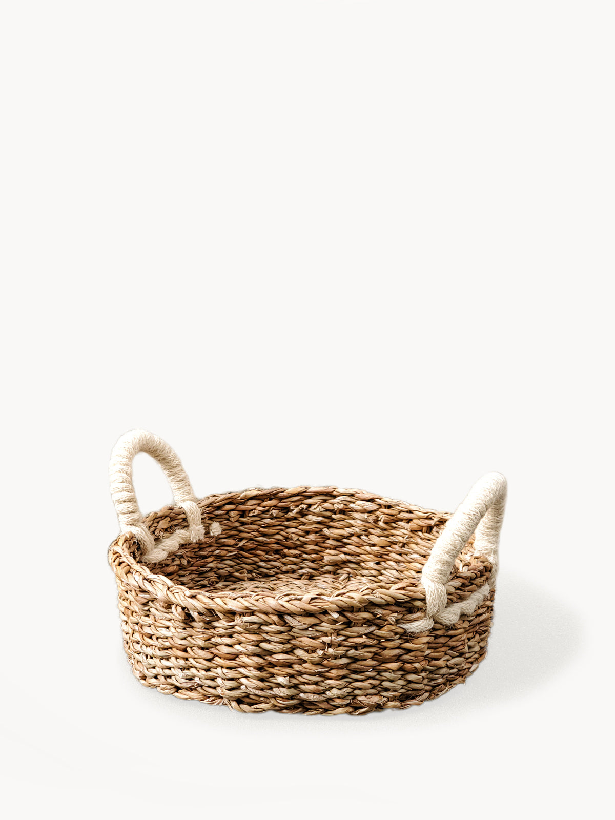 Savar Round Bread Basket made from seagrass and jute, showcasing its natural and white colors, perfect for serving bread or organizing items.