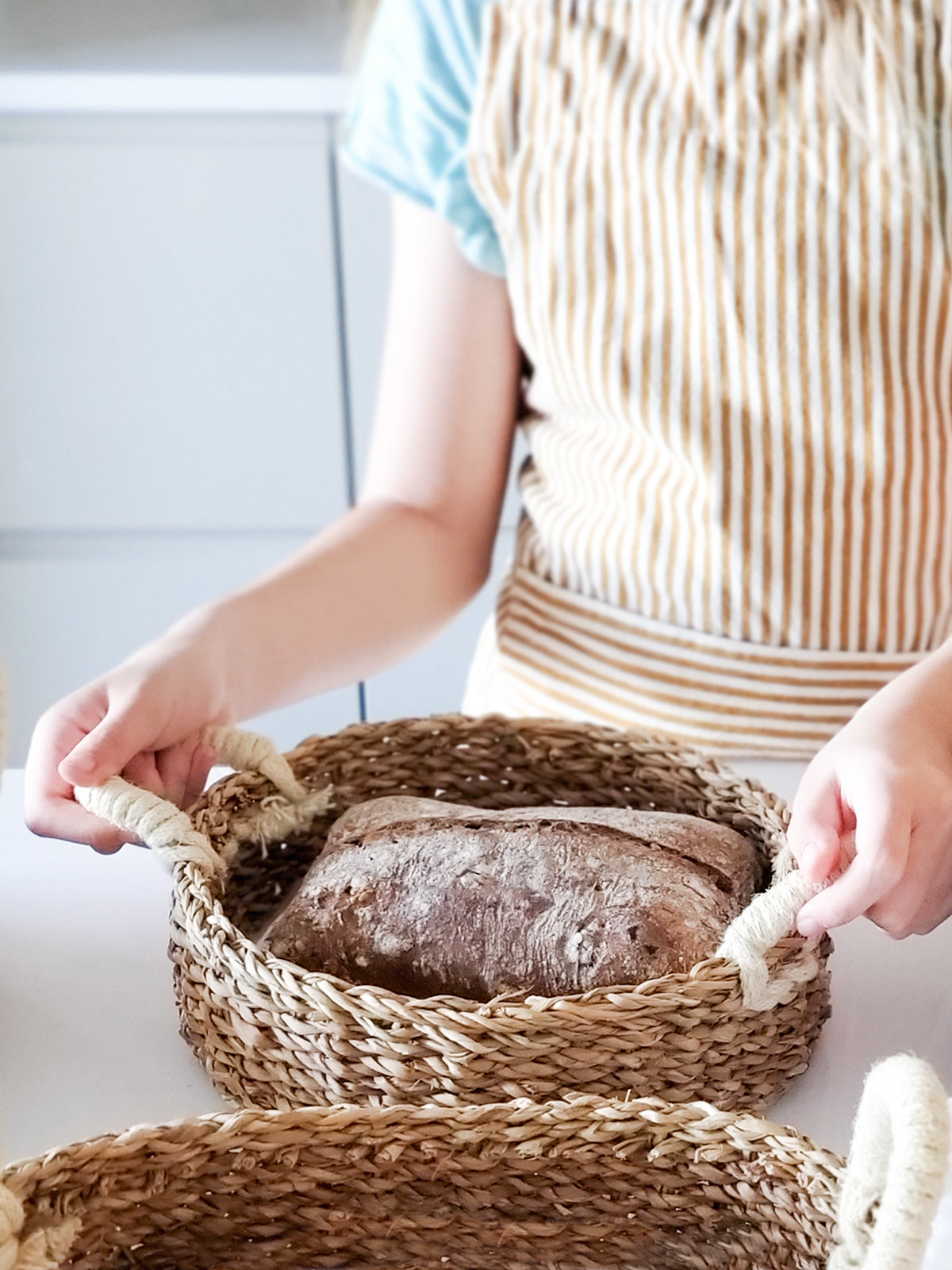 Savar Round Bread Basket made from seagrass and jute, showcasing its natural and white colors, perfect for serving bread or organizing items.