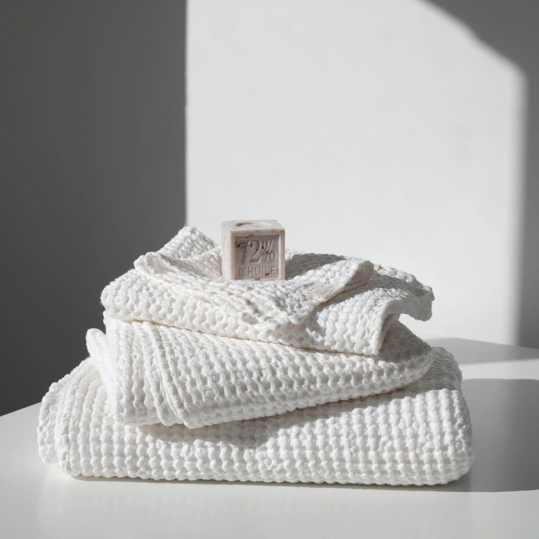 Set of three crispy white waffle linen towels in various sizes, showcasing their soft texture and absorbent quality.