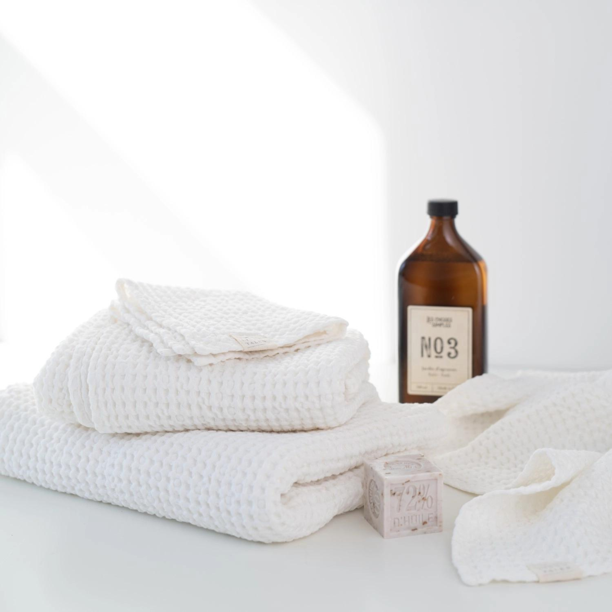 Set of three crispy white waffle linen towels in various sizes, showcasing their soft texture and absorbent quality.