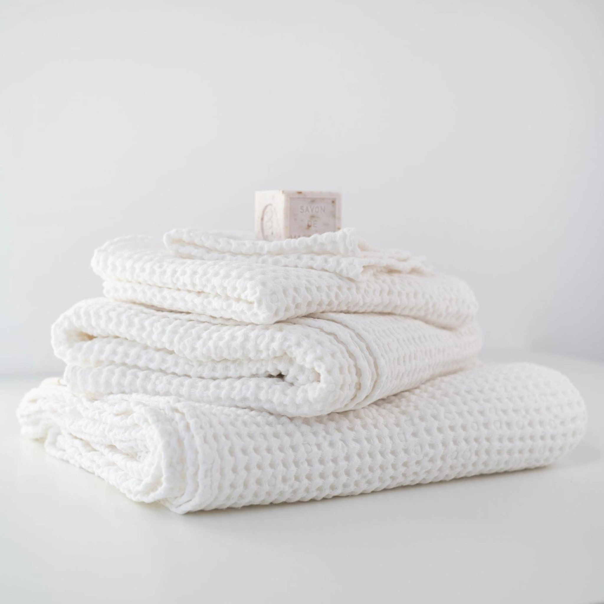 Set of three crispy white waffle linen towels in various sizes, showcasing their soft texture and absorbent quality.