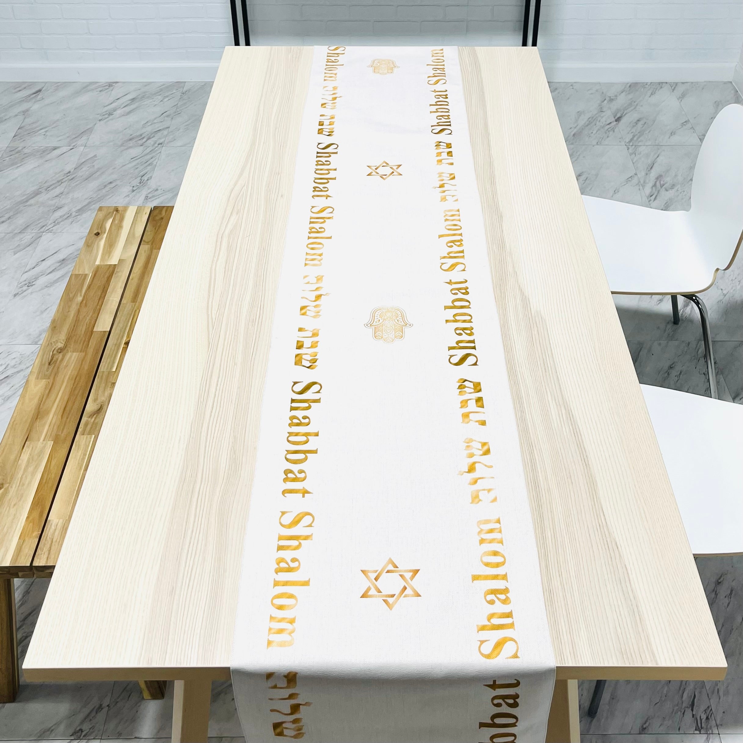 Elegant cream-colored Shabbat Shalom table runner featuring Stars of David and Hamsa symbols, perfect for festive dining.