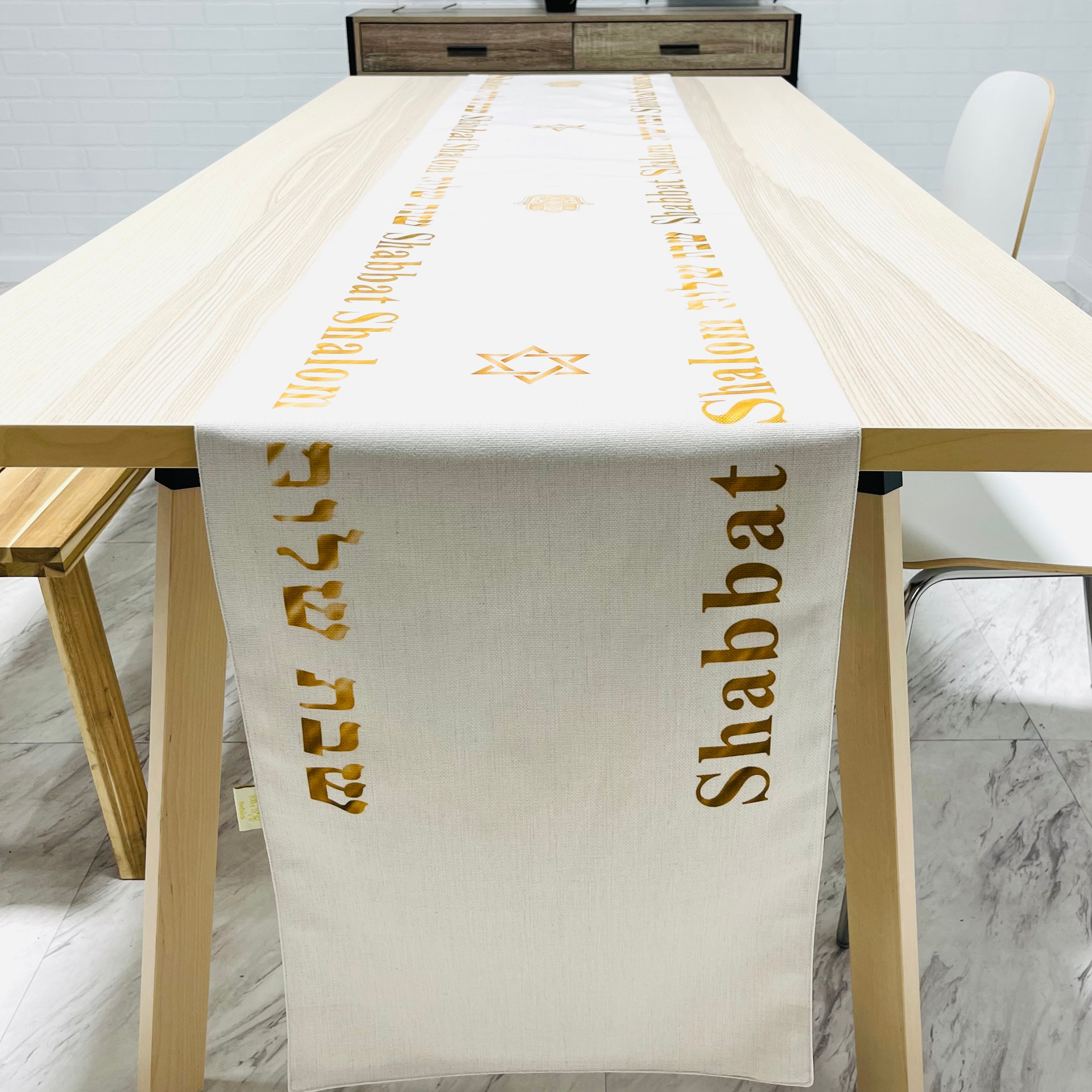 Elegant cream-colored Shabbat Shalom table runner featuring Stars of David and Hamsa symbols, perfect for festive dining.