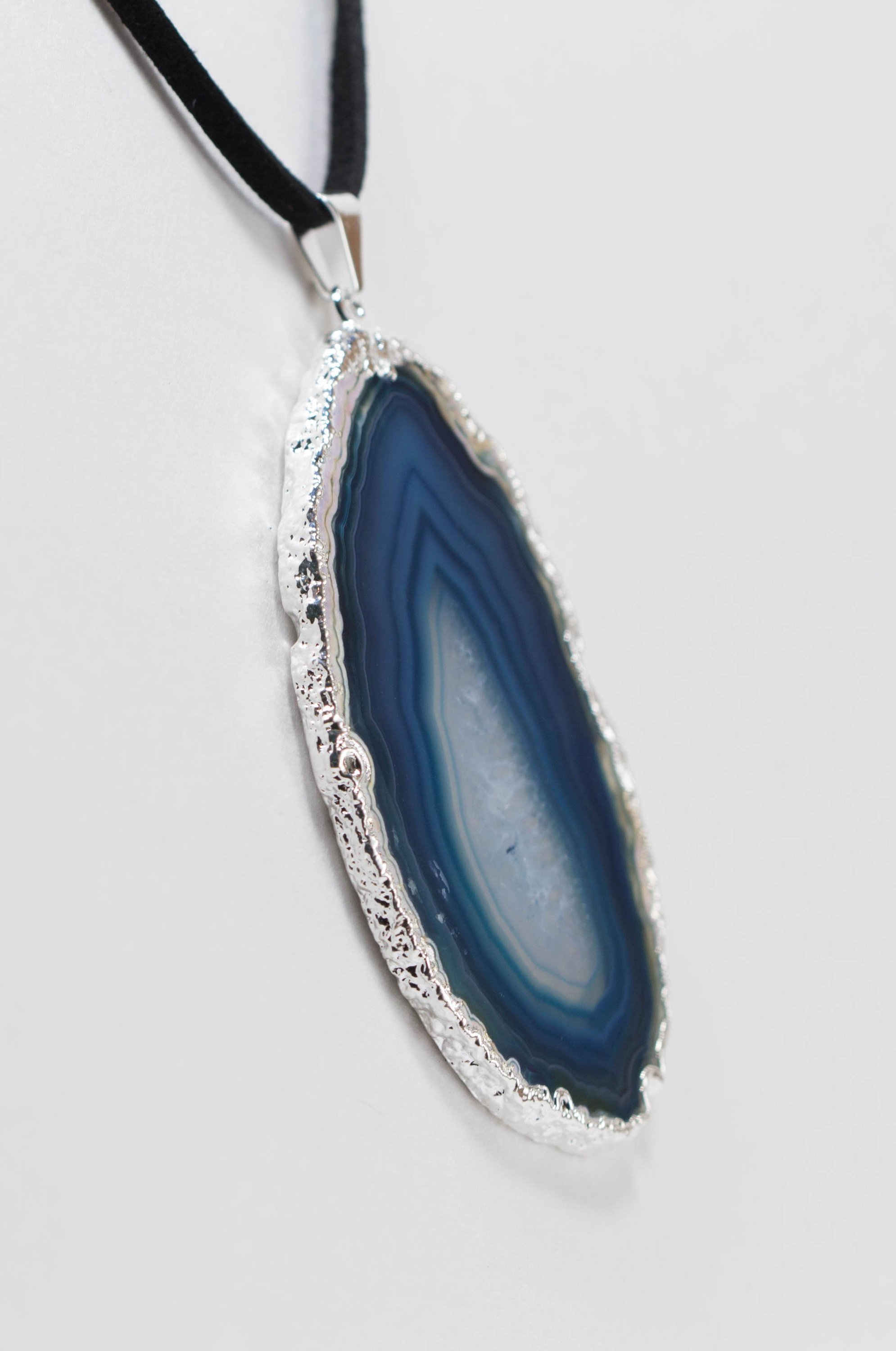 A stylish silver electroplated agate slice pendant hanging from a leather cord, showcasing vibrant colors and unique patterns.