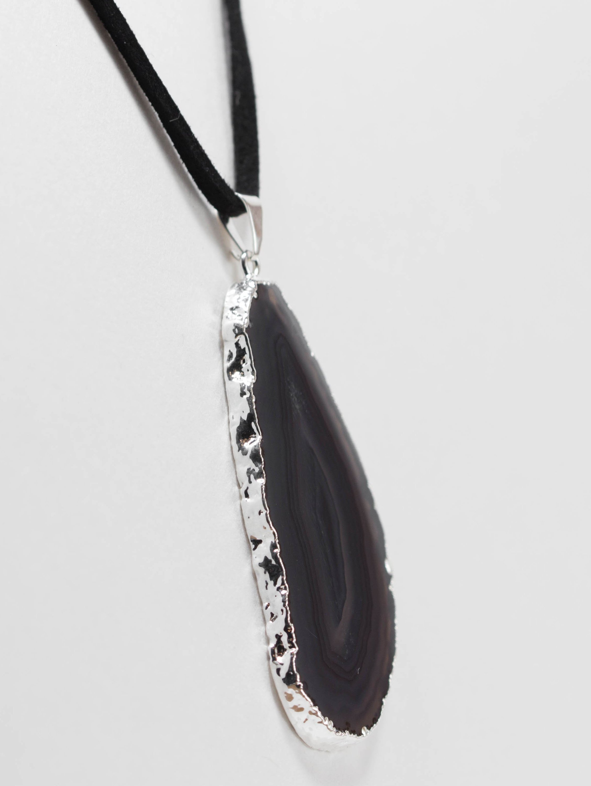 A stylish silver electroplated agate slice pendant hanging from a leather cord, showcasing vibrant colors and unique patterns.