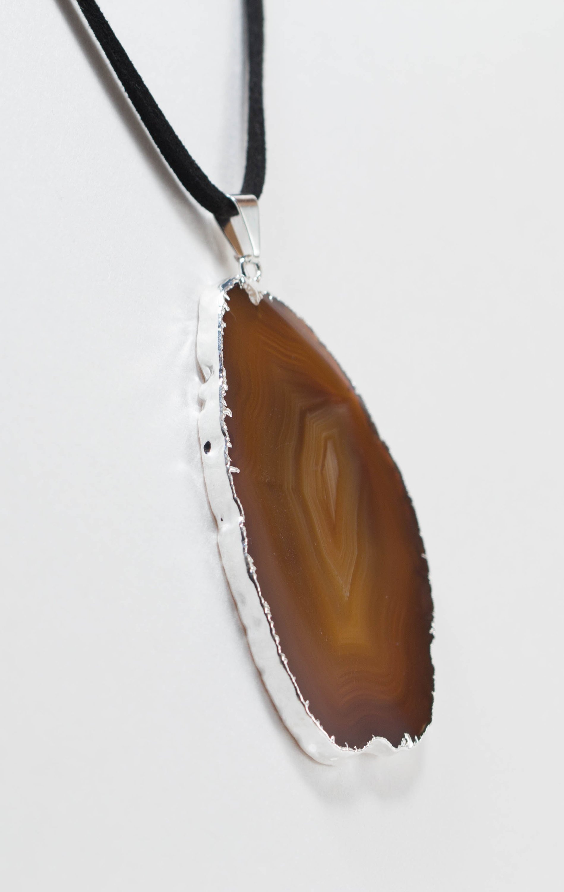 A stylish silver electroplated agate slice pendant hanging from a leather cord, showcasing vibrant colors and unique patterns.