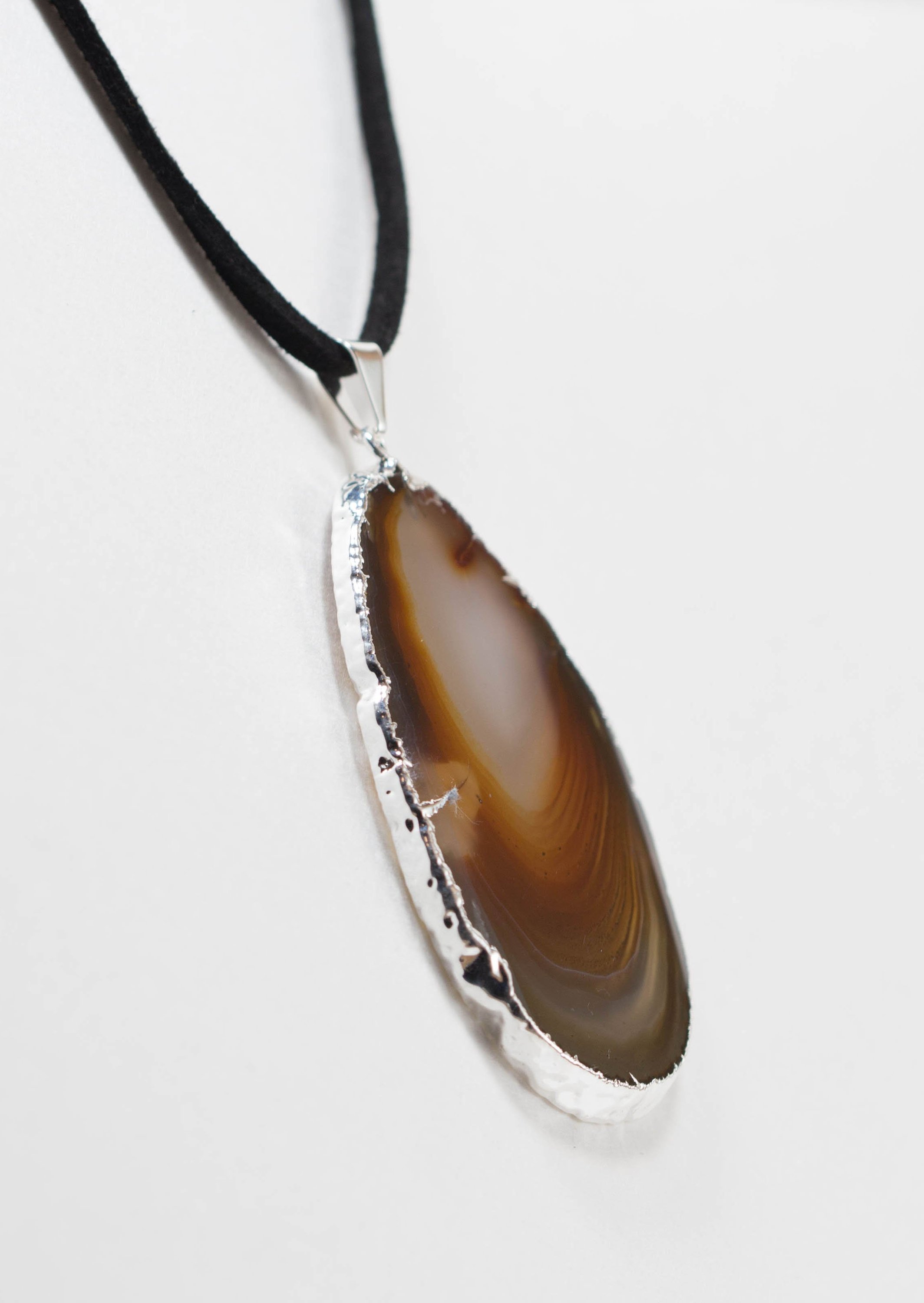 A stylish silver electroplated agate slice pendant hanging from a leather cord, showcasing vibrant colors and unique patterns.