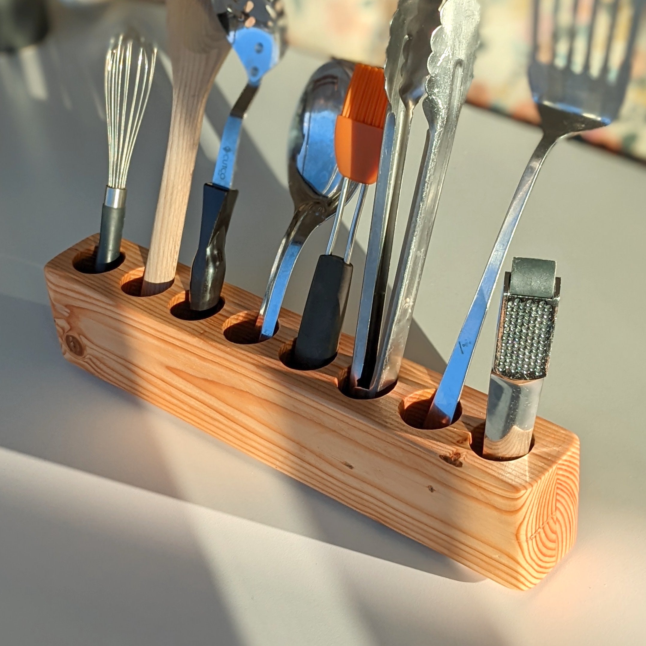 Slot cooking utensil holder made from Doug Fir wood, featuring a narrow design to save counter space and store up to eight utensils.