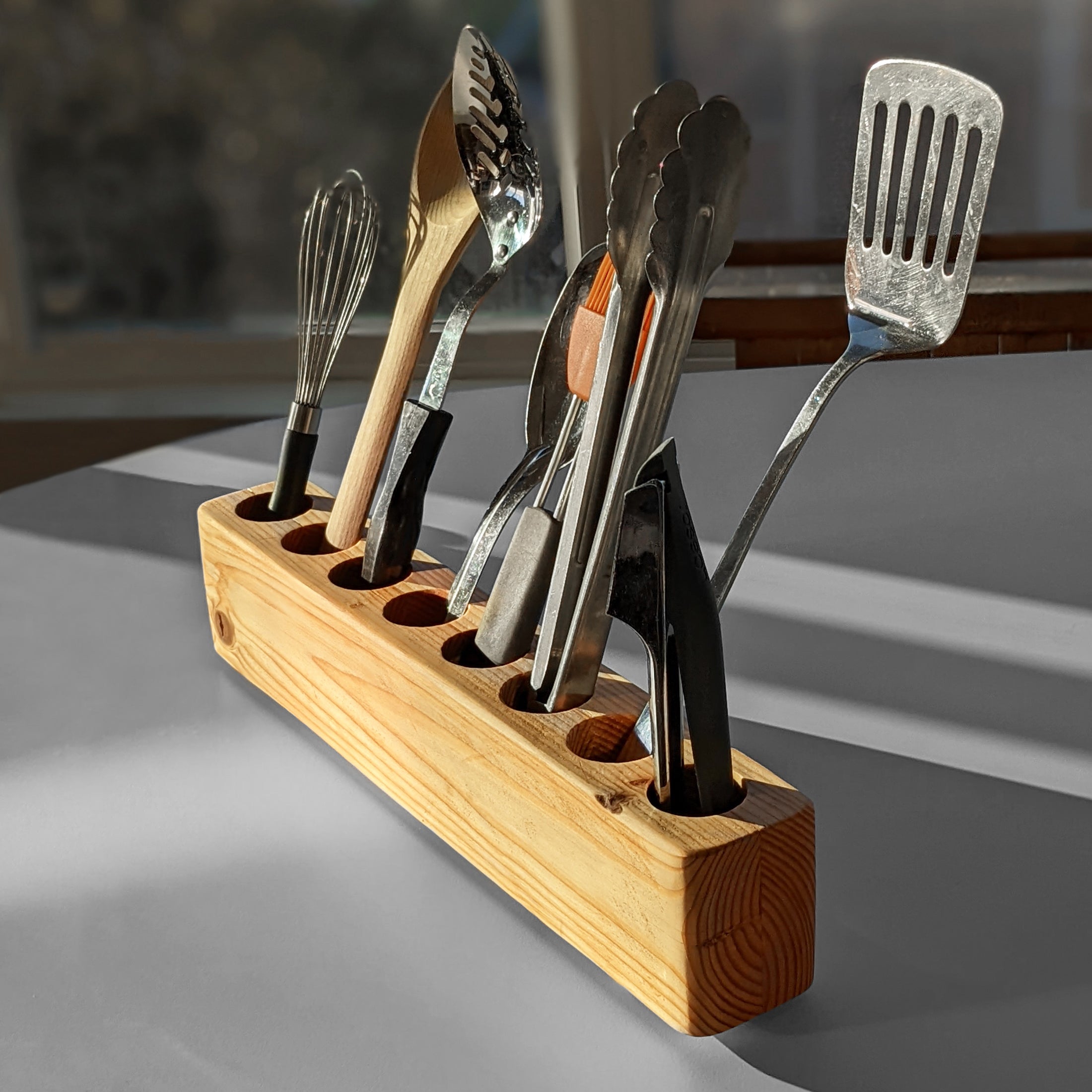 Slot cooking utensil holder made from Doug Fir wood, featuring a narrow design to save counter space and store up to eight utensils.