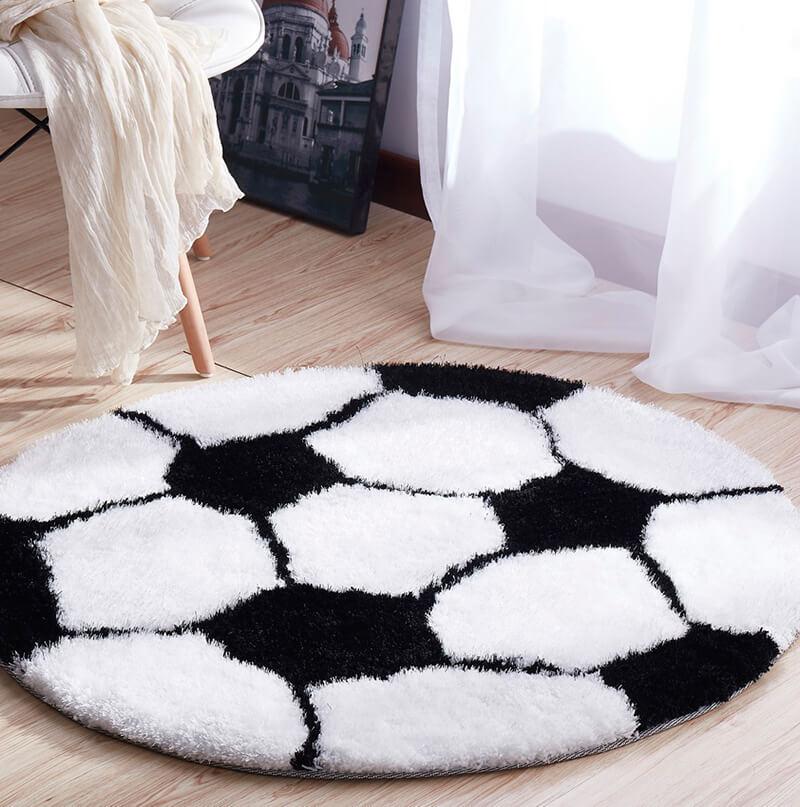 A soft shaggy decorative area rug shaped like a soccer ball, featuring a black and white color scheme, perfect for kids' rooms.