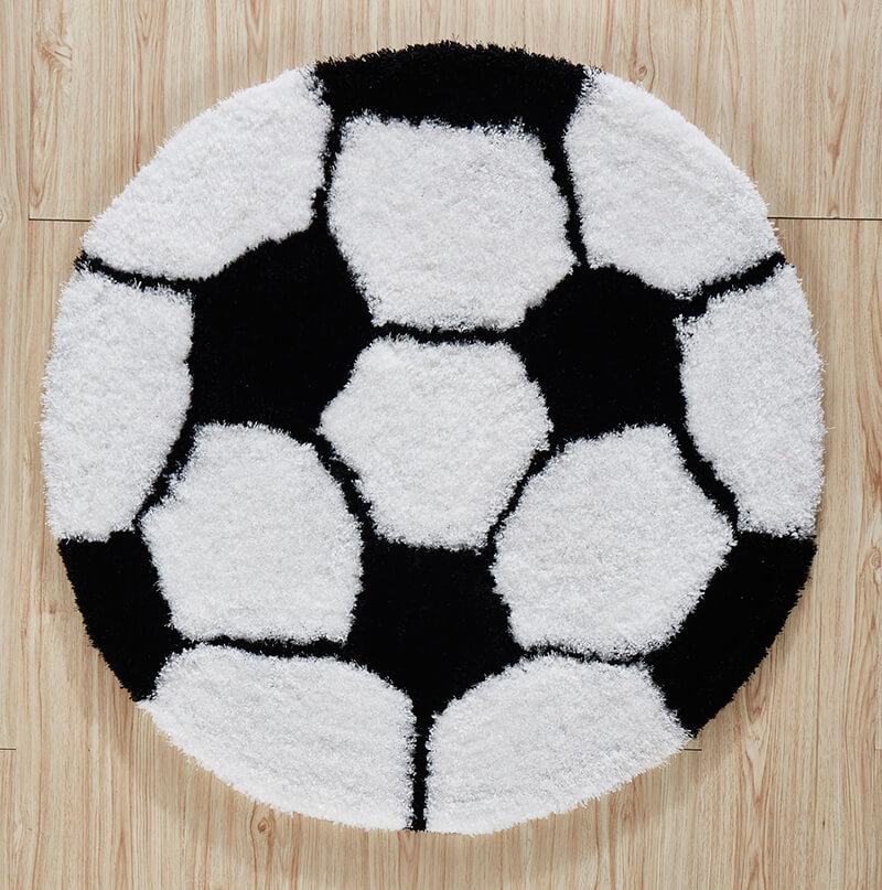 A soft shaggy decorative area rug shaped like a soccer ball, featuring a black and white color scheme, perfect for kids' rooms.