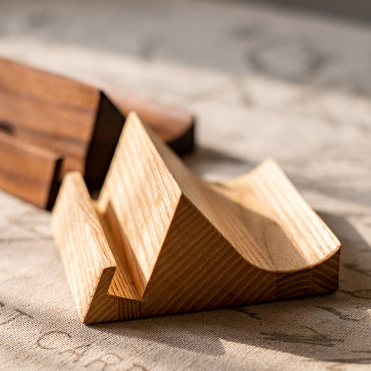 A handcrafted solid wood cellphone stand made from white ash, cherry, or walnut, showcasing its unique design and natural finish.