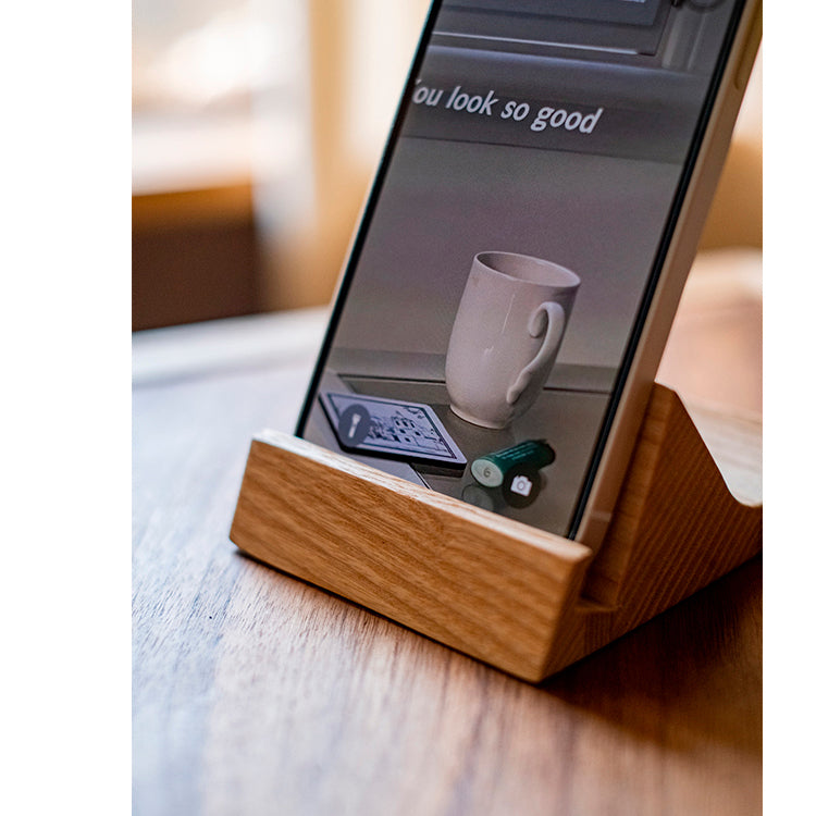 A handcrafted solid wood cellphone stand made from white ash, cherry, or walnut, showcasing its unique design and natural finish.