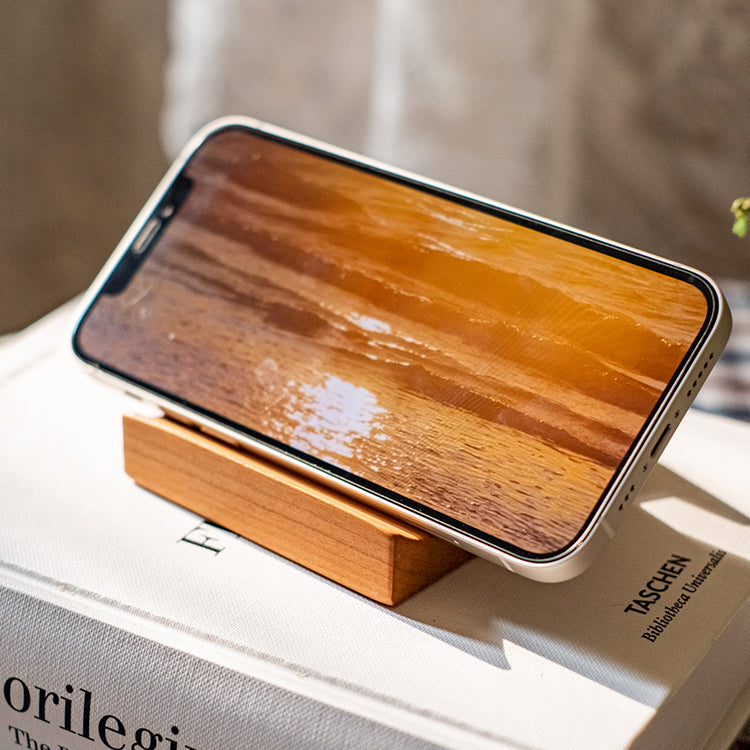 A handcrafted solid wood cellphone stand made from white ash, cherry, or walnut, showcasing its unique design and natural finish.