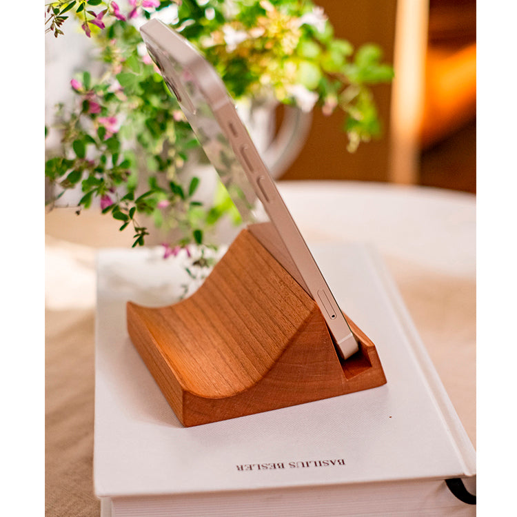 A handcrafted solid wood cellphone stand made from white ash, cherry, or walnut, showcasing its unique design and natural finish.