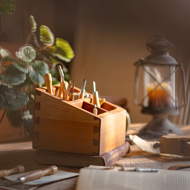 A handcrafted solid wood desktop organizer in natural brown, featuring compartments for pens and small office supplies.