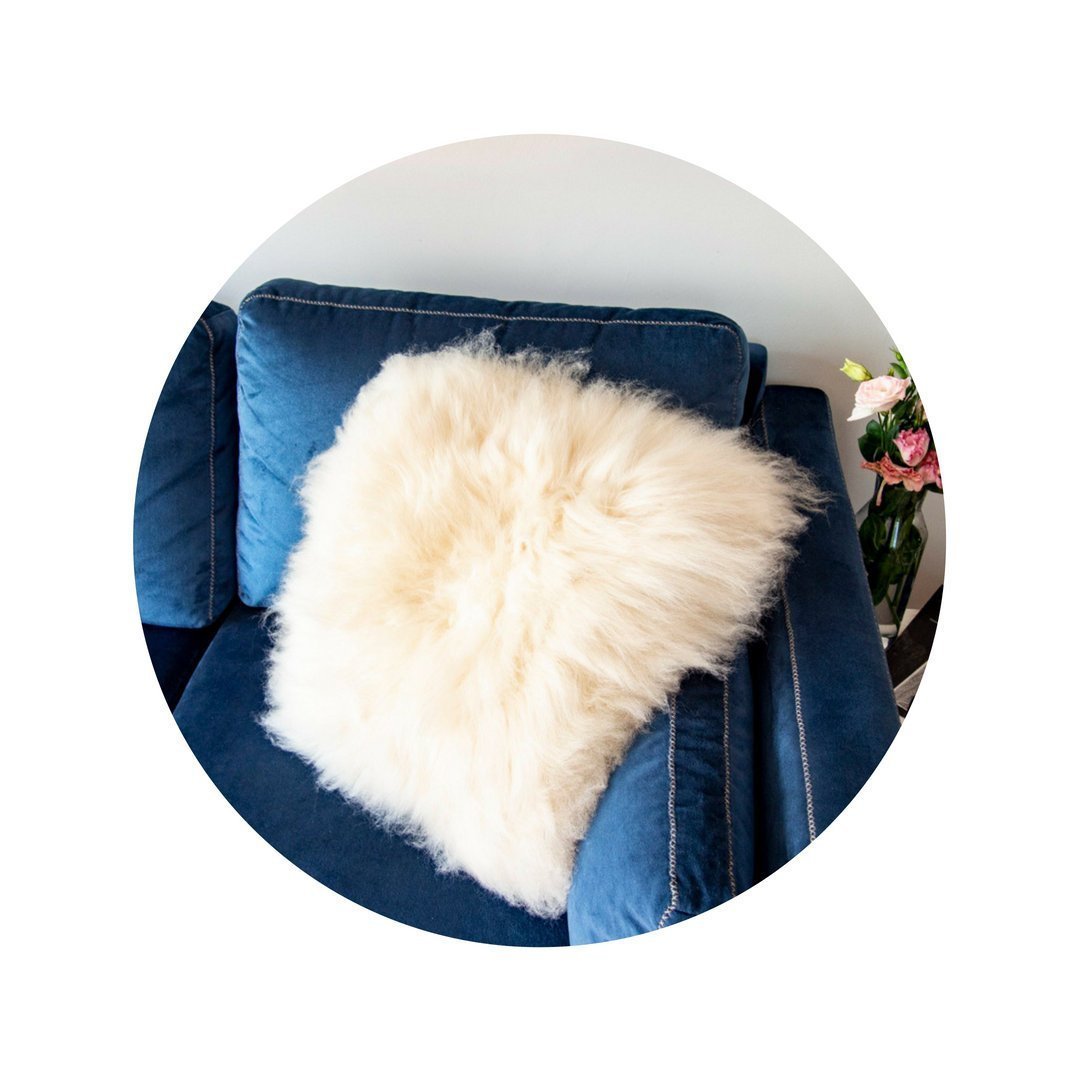 A luxurious square furry pillow made from 100% natural sheepskin, showcasing its soft and fluffy texture in a cozy setting.