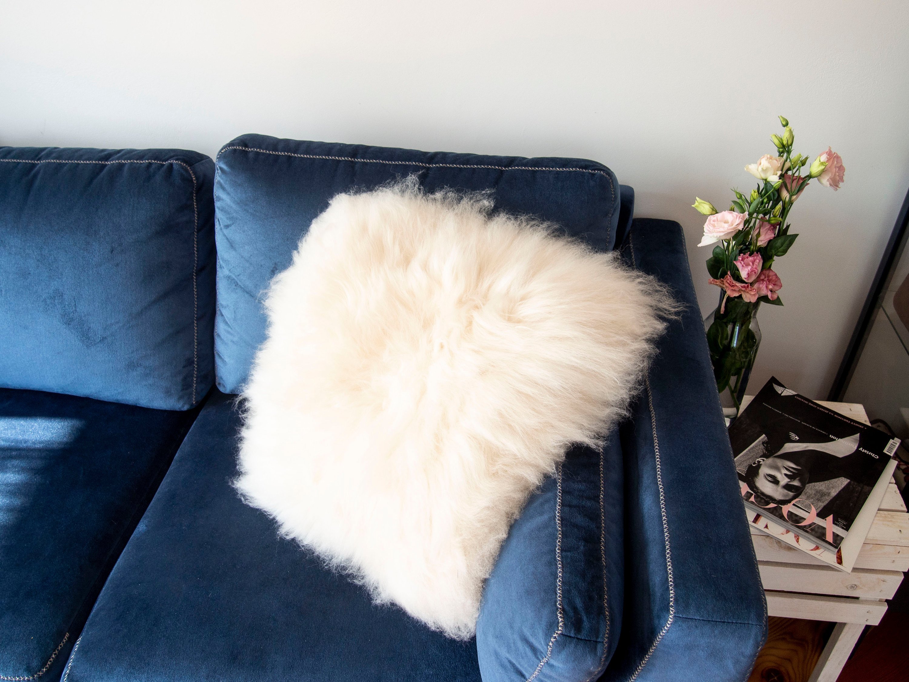 A luxurious square furry pillow made from 100% natural sheepskin, showcasing its soft and fluffy texture in a cozy setting.