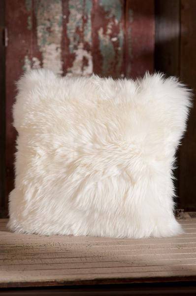 A luxurious square furry pillow made from 100% natural sheepskin, showcasing its soft and fluffy texture in a cozy setting.