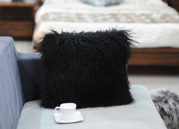 A luxurious square furry pillow made from 100% natural sheepskin, showcasing its soft and fluffy texture in a cozy setting.