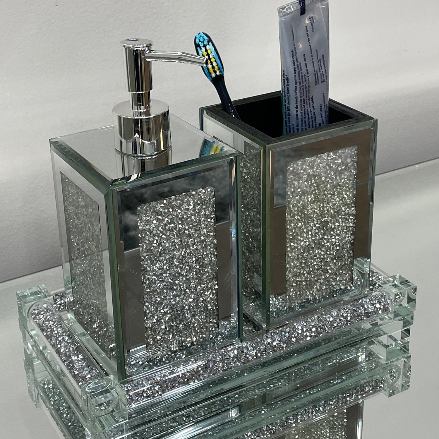 Square soap dispenser and toothbrush holder set in silver crushed diamond design, featuring chrome accents and an elegant tray.