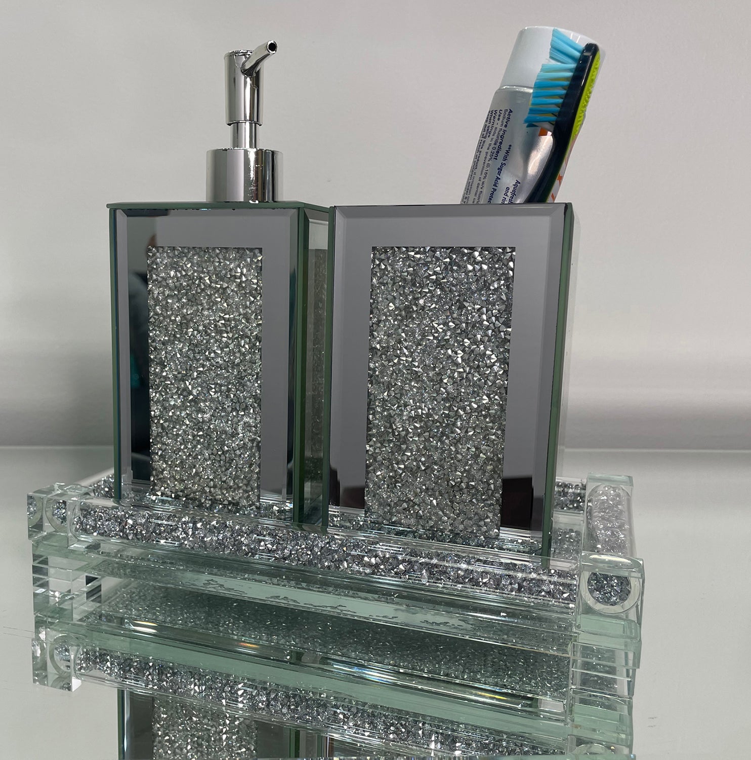 Square soap dispenser and toothbrush holder set in silver crushed diamond design, featuring chrome accents and an elegant tray.