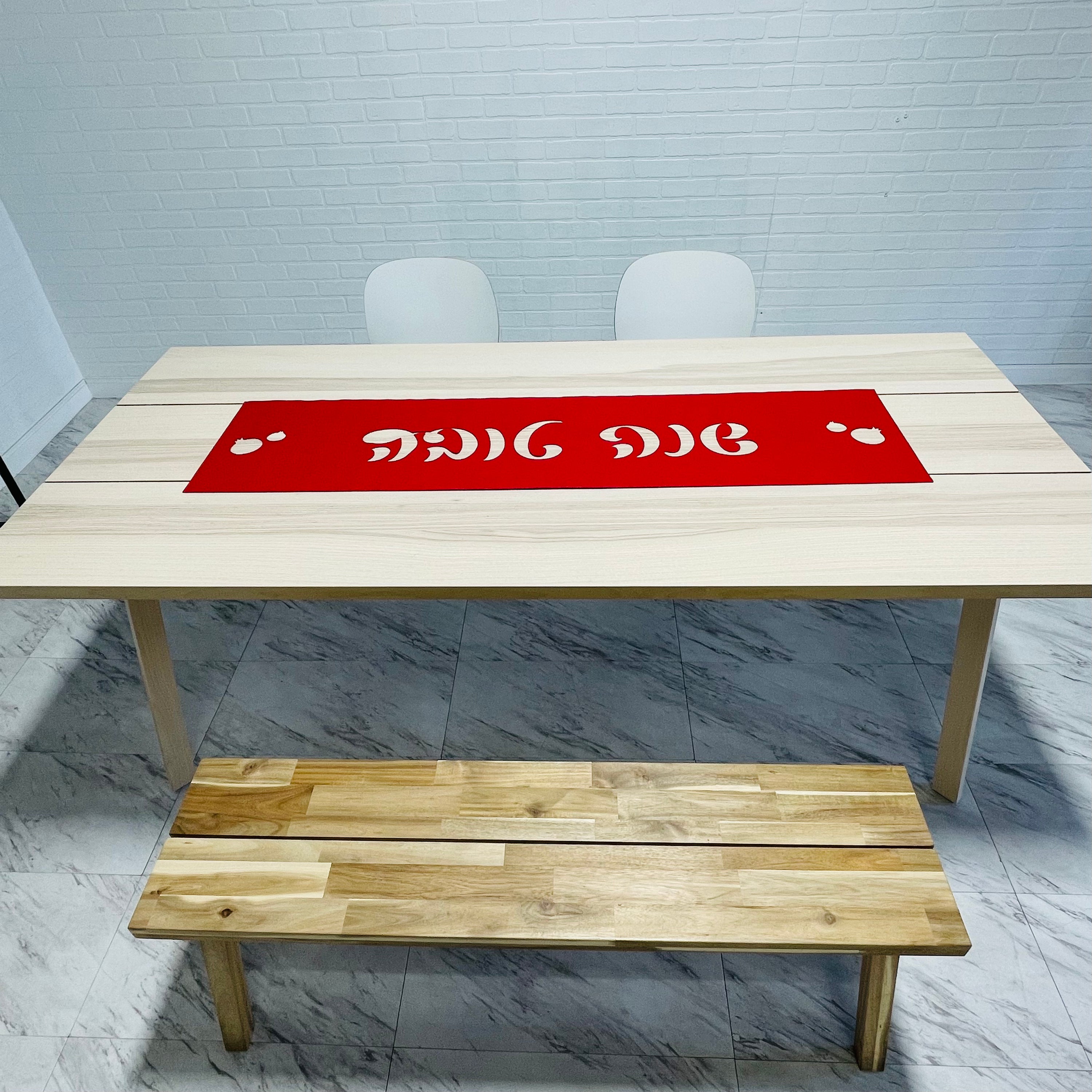 A vibrant laser cut vinyl table runner featuring 'Shana Tova' in Hebrew script, adorned with decorative pomegranates, perfect for Rosh Hashanah.