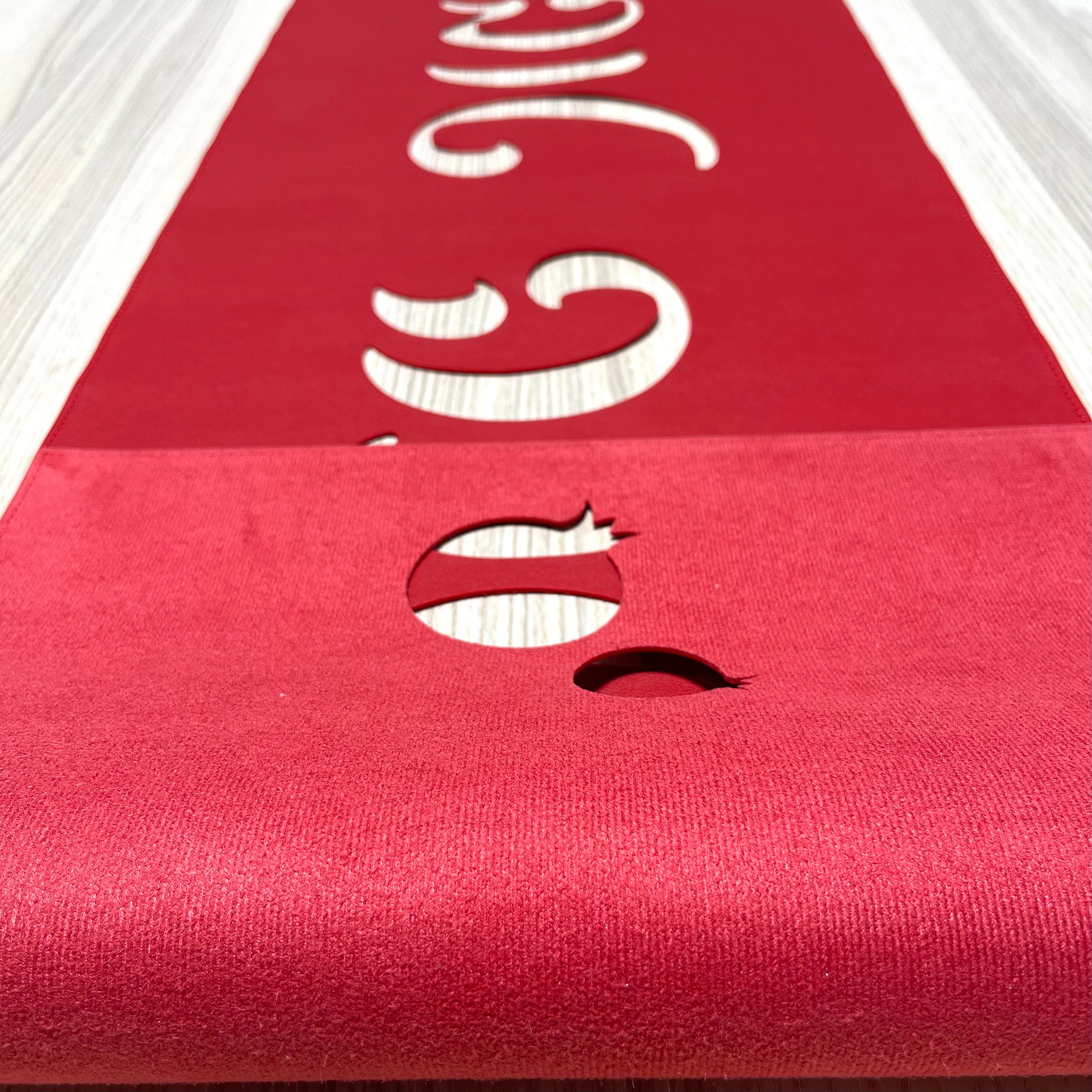 A vibrant laser cut vinyl table runner featuring 'Shana Tova' in Hebrew script, adorned with decorative pomegranates, perfect for Rosh Hashanah.