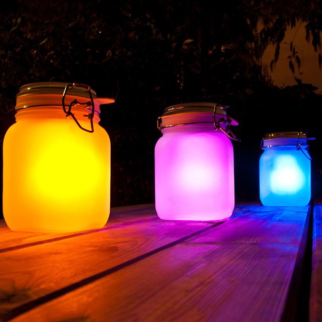 Colorful illuminated jars on table.