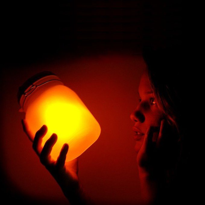 Person holding glowing jar.