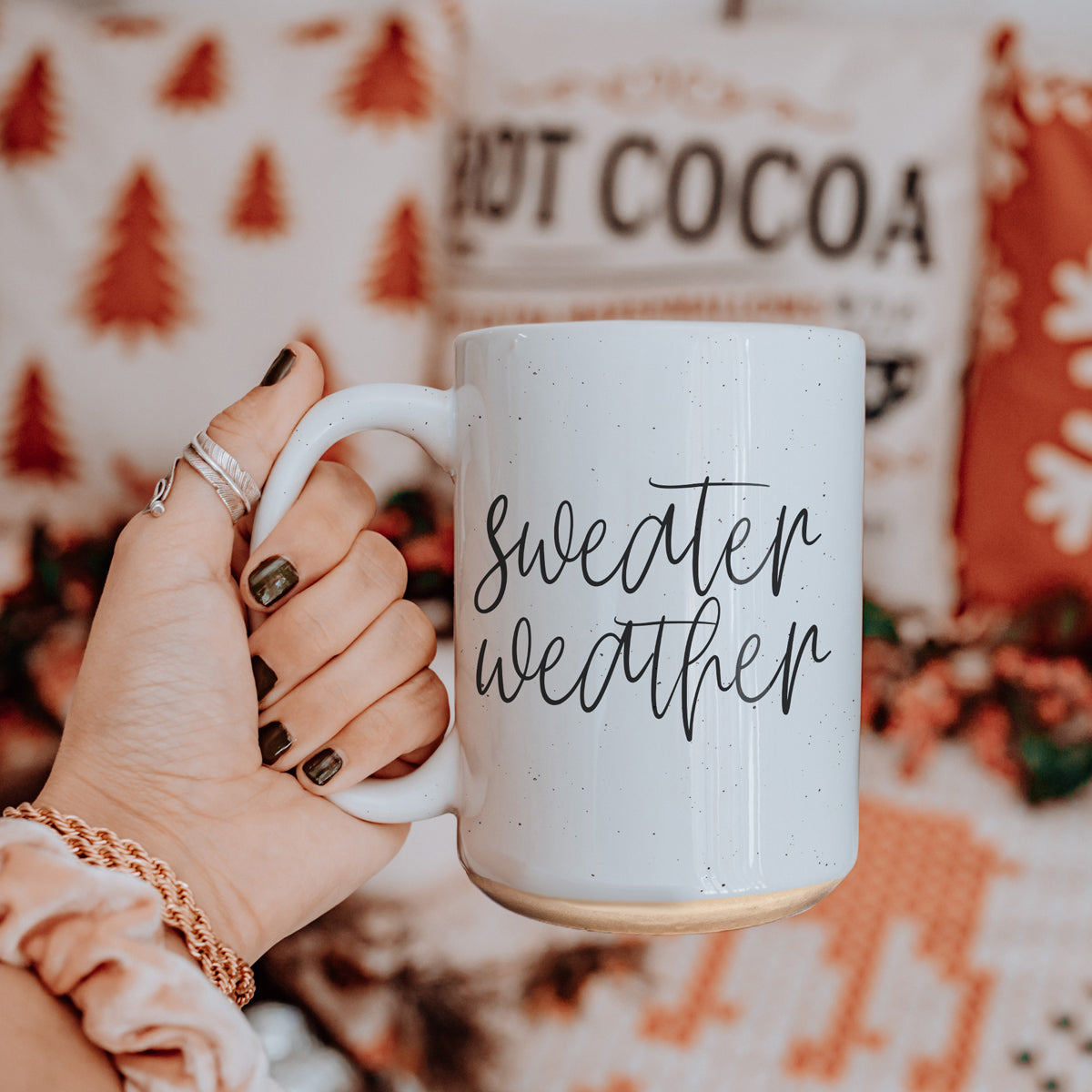 A cozy off-white ceramic mug with dark speckles, featuring a stylish black graphic that reads 'Sweater Weather', perfect for warm beverages.