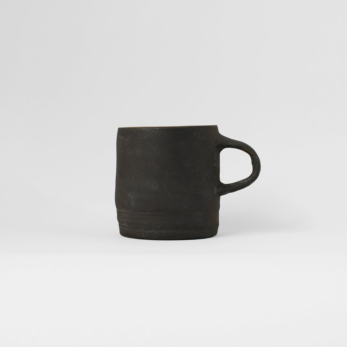 A unique handmade black ceramic mug by Gunvor Tangrand, inspired by Lofoten nature, showcasing artisanal craftsmanship.