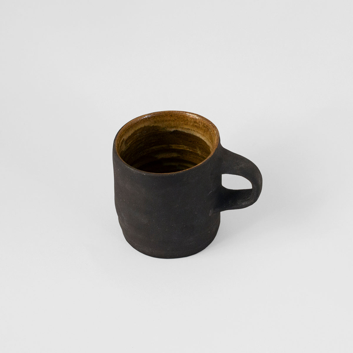 A unique handmade black ceramic mug by Gunvor Tangrand, inspired by Lofoten nature, showcasing artisanal craftsmanship.