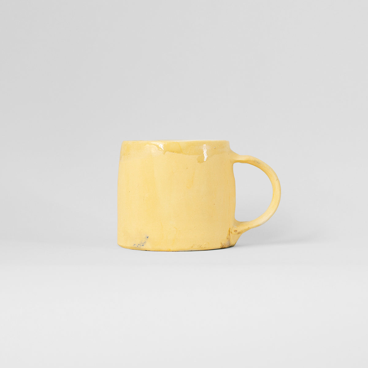 A vibrant yellow handmade ceramic mug by Gunvor Tangrand, showcasing unique glaze and design inspired by Lofoten's nature.