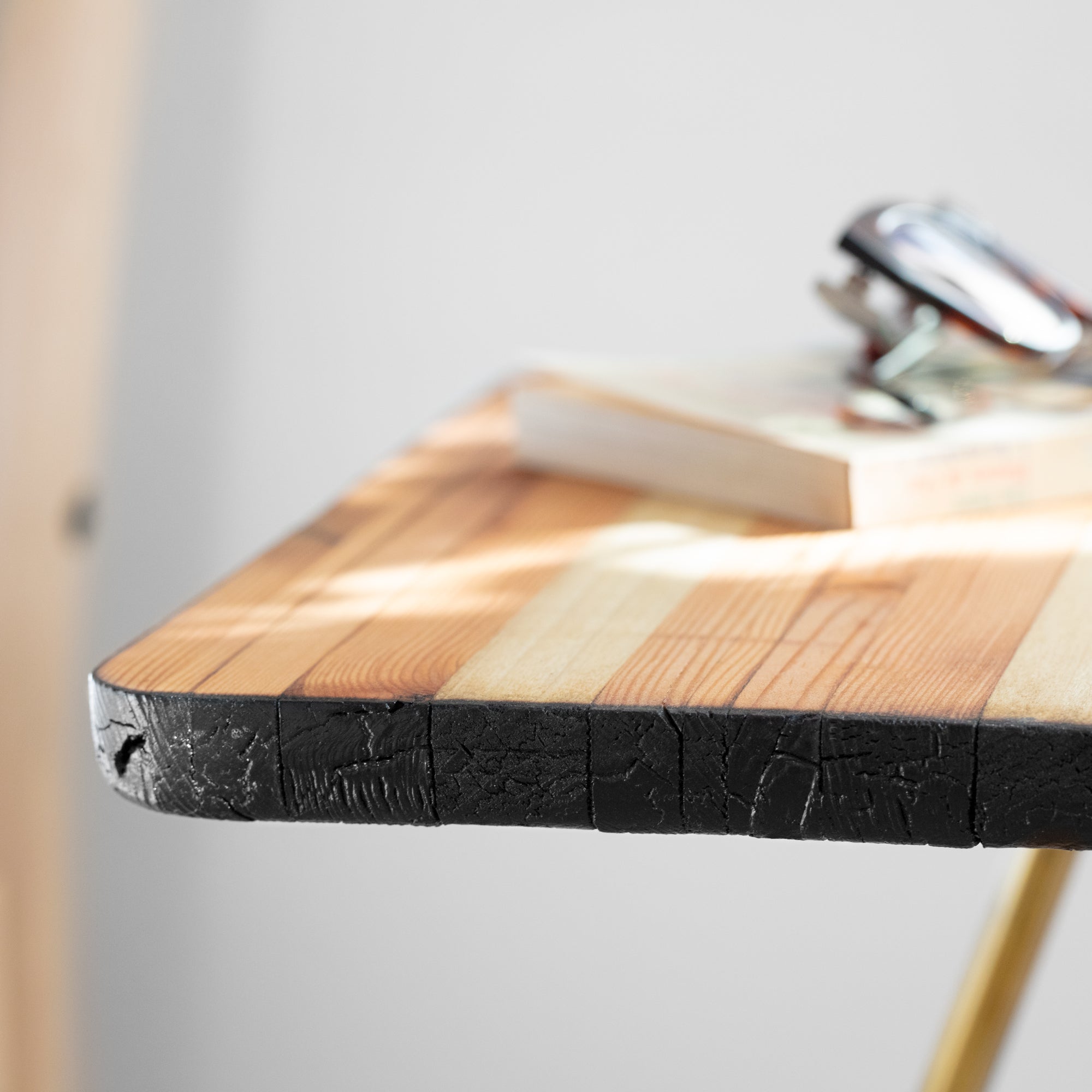 Tantric side table featuring sleek brass legs and a reclaimed wood top with a torched black and natural finish.