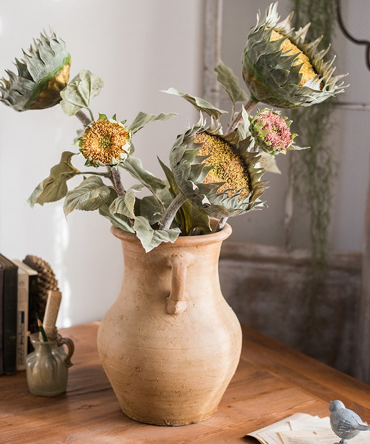 A beautiful handmade artificial sunflower stem with vibrant yellow petals, green leaves, and a brown stem, perfect for home decor.