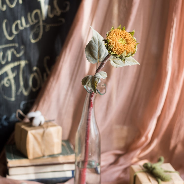 A beautiful handmade artificial sunflower stem with vibrant yellow petals, green leaves, and a brown stem, perfect for home decor.