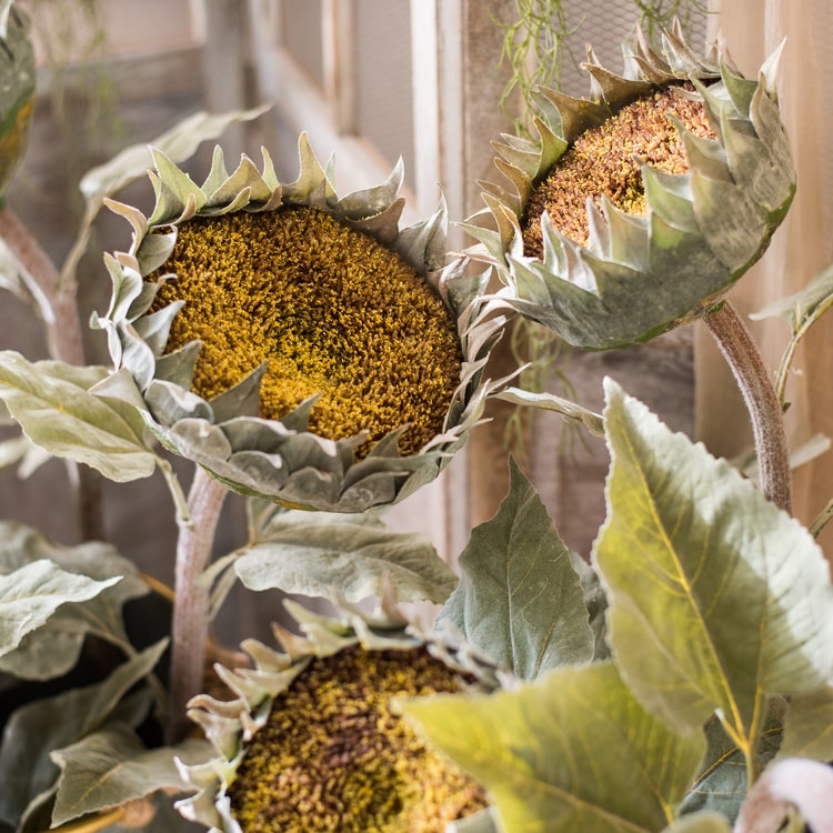 A beautiful handmade artificial sunflower stem with vibrant yellow petals, green leaves, and a brown stem, perfect for home decor.