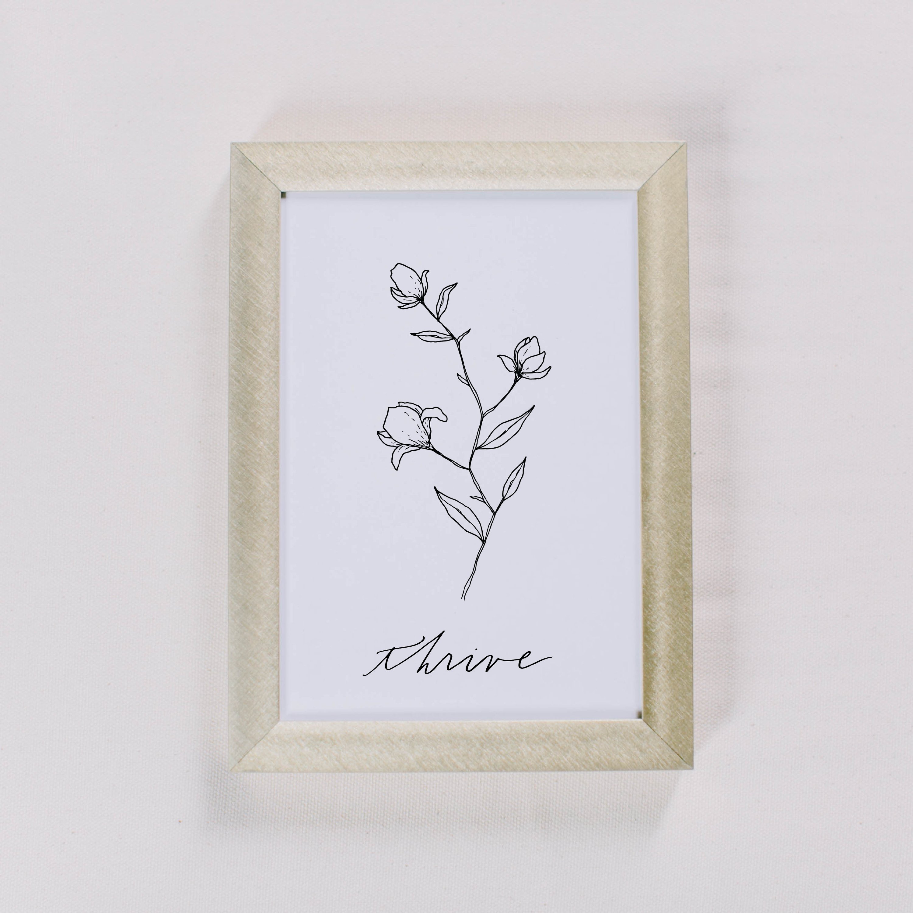 Thrive Wildflower Print featuring unique floral design and calligraphy by Alyssa Thiel, displayed in a gold metal frame.