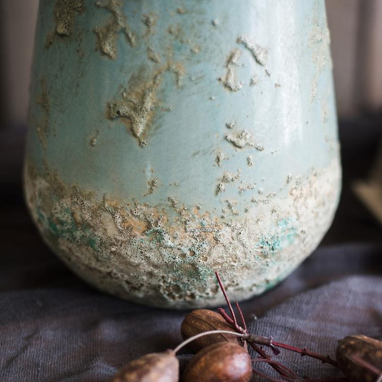 A beautifully handcrafted turquoise ceramic vase with a textured finish, showcasing unique color variations.