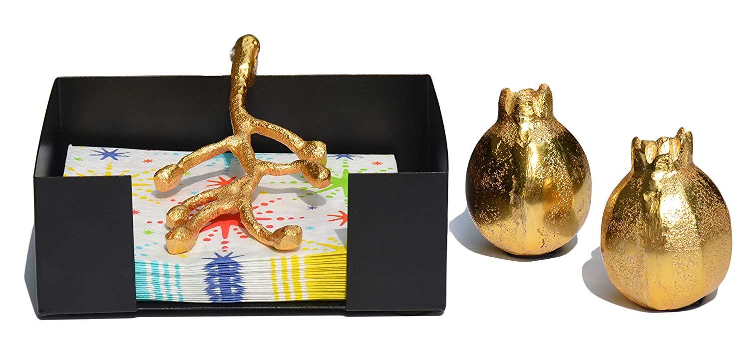 Handcrafted golden napkin holder with olive bud design and unique pomegranate salt and pepper shakers, elegantly displayed on a dining table.