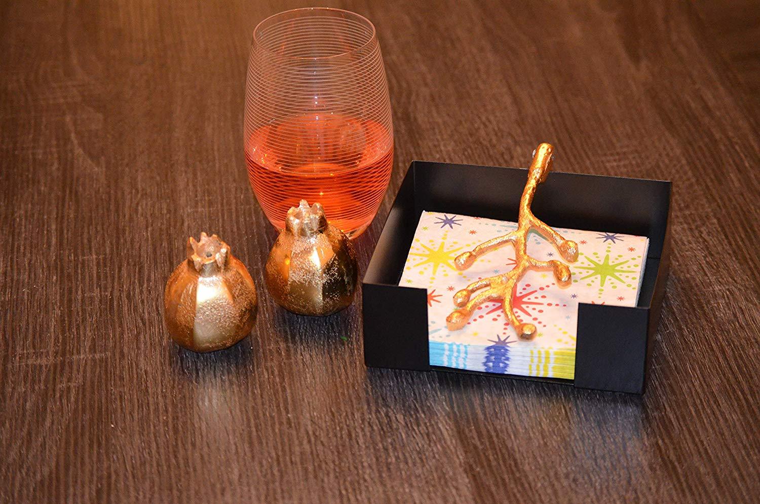 Handcrafted golden napkin holder with olive bud design and unique pomegranate salt and pepper shakers, elegantly displayed on a dining table.